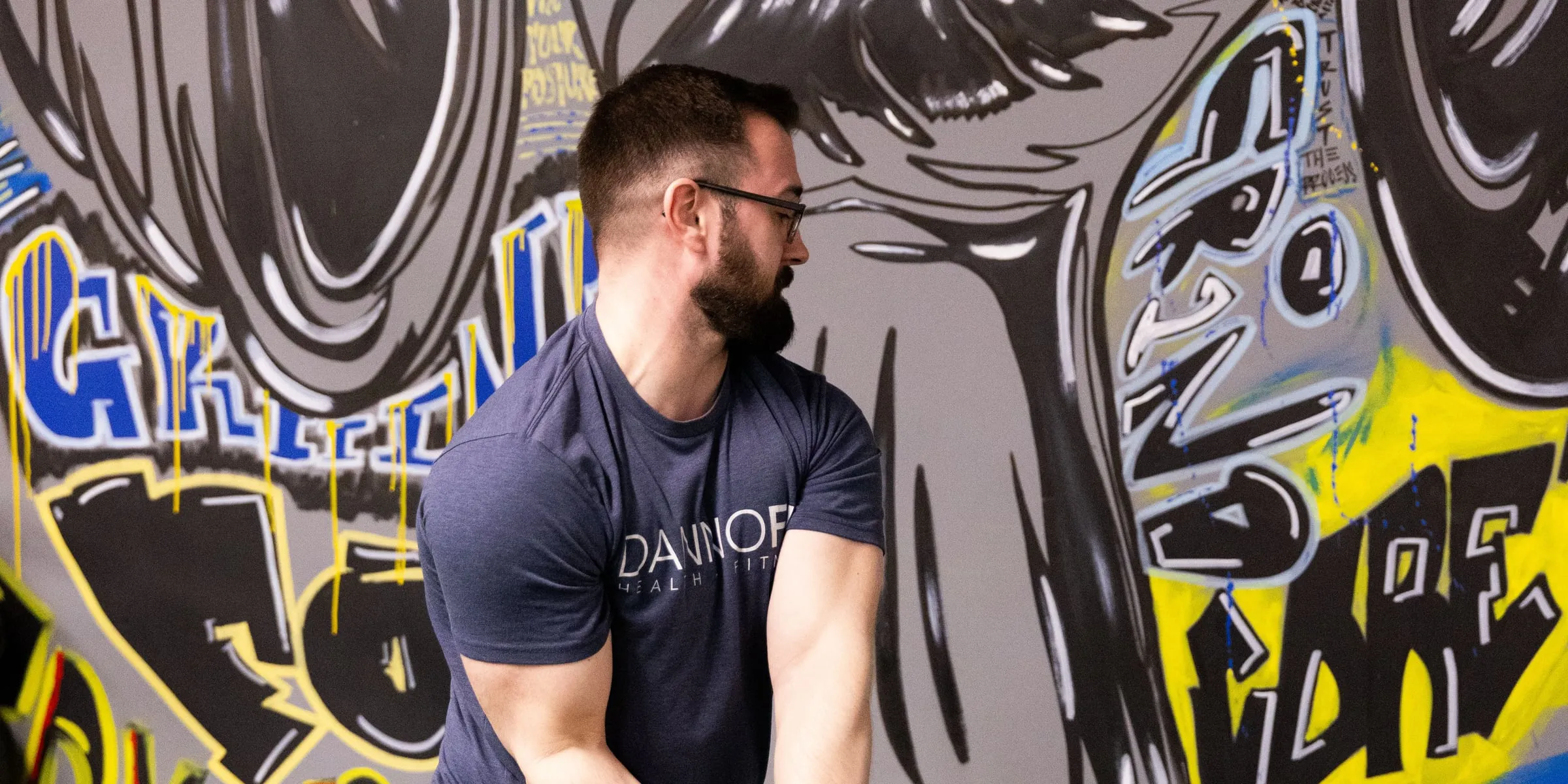 A DANNOFIT coach training in front of the gym's mural